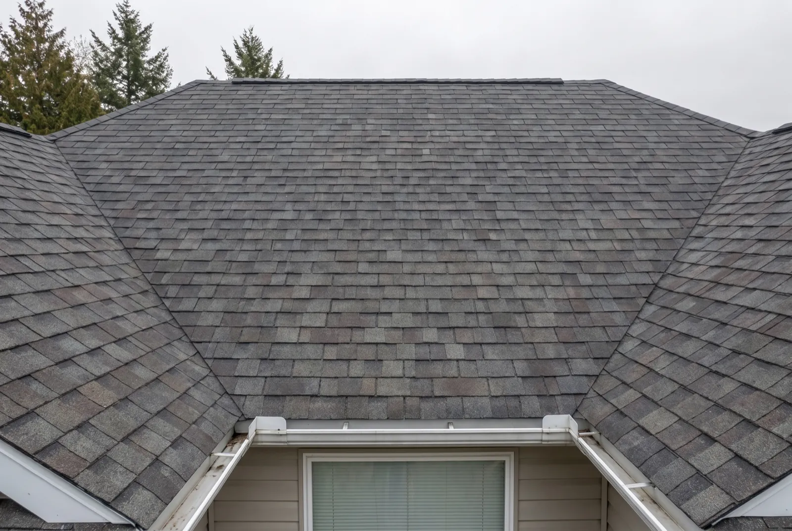 The same roof from the same position after replacement, covered in new charcoal architectural shingles with clean valleys and a new ridge line